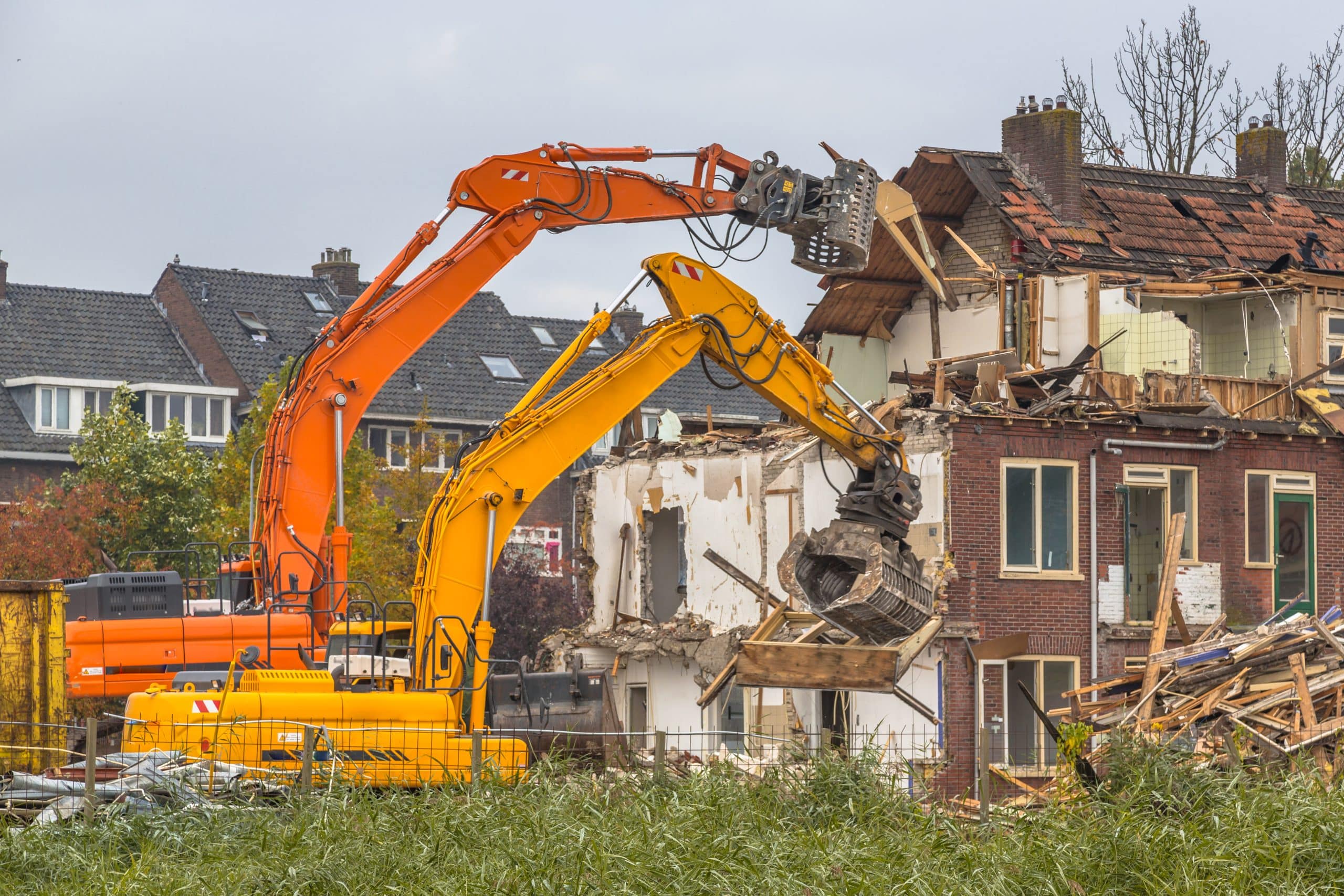 Two demolition cranes at work on an industrial site