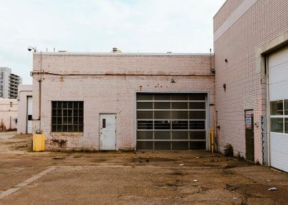 Industrial garage exterior showcasing urban decay with brick walls and graffiti.
