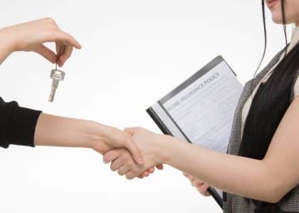 Contractor and property owner reviewing insurance documents and shaking hands