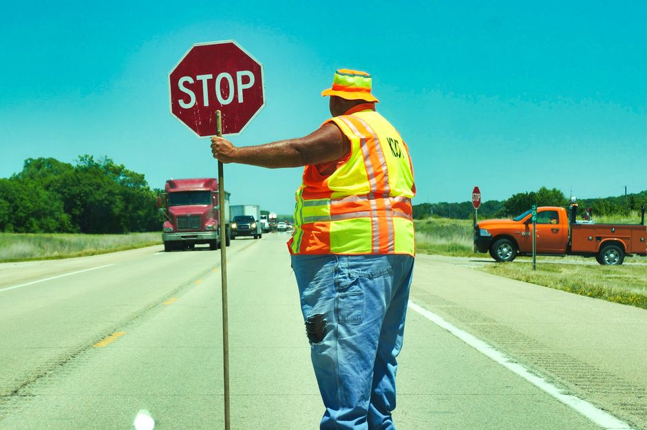 flagger directing traffic near a demolition site entrance